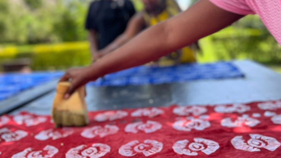 Person working with a red fabric with white patterns outdoors